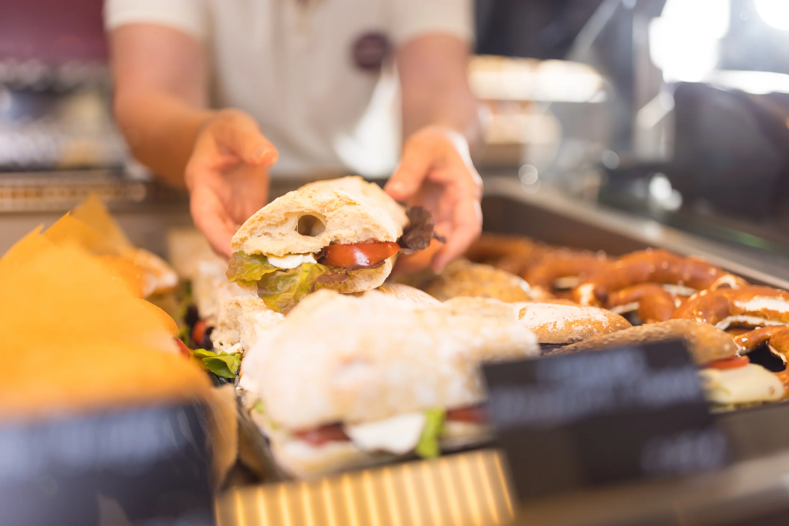 Feinsinn Mitarbeiterin zeigt belegtes Brot aus der Bäckertheke