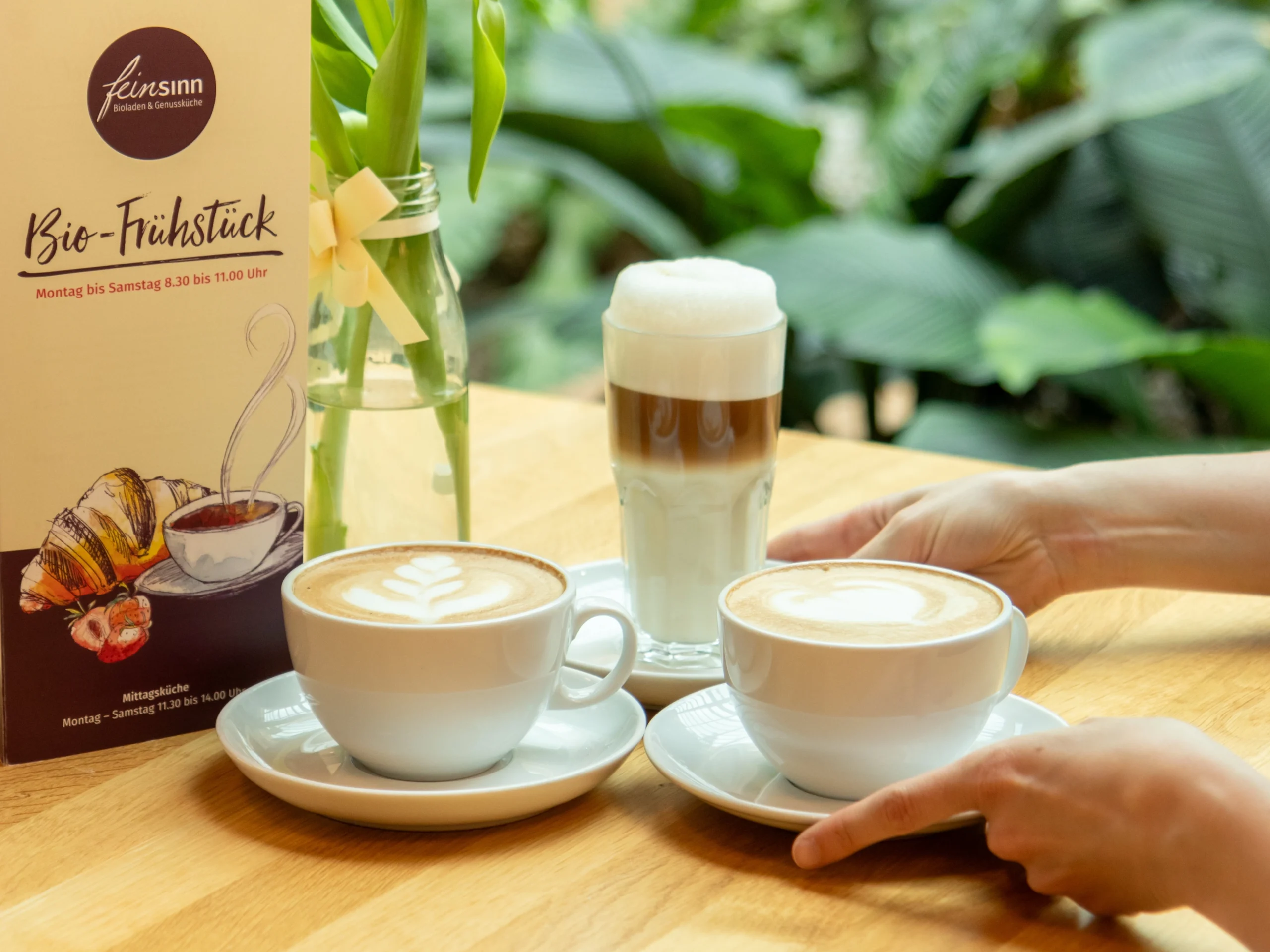 Person stellt Kaffeetasse zu weiteren Tassen auf den Tisch