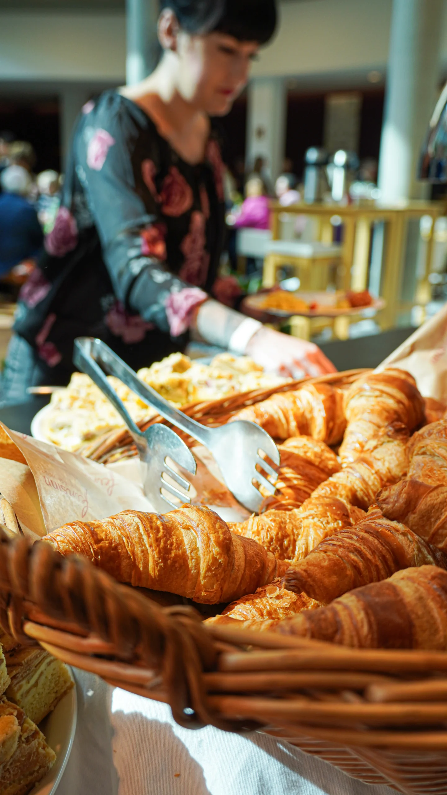 Croissants mit Zange am Frühstücksbuffet